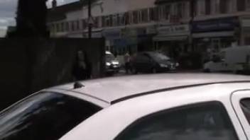 Young woman urinating on the road behind the vehicle